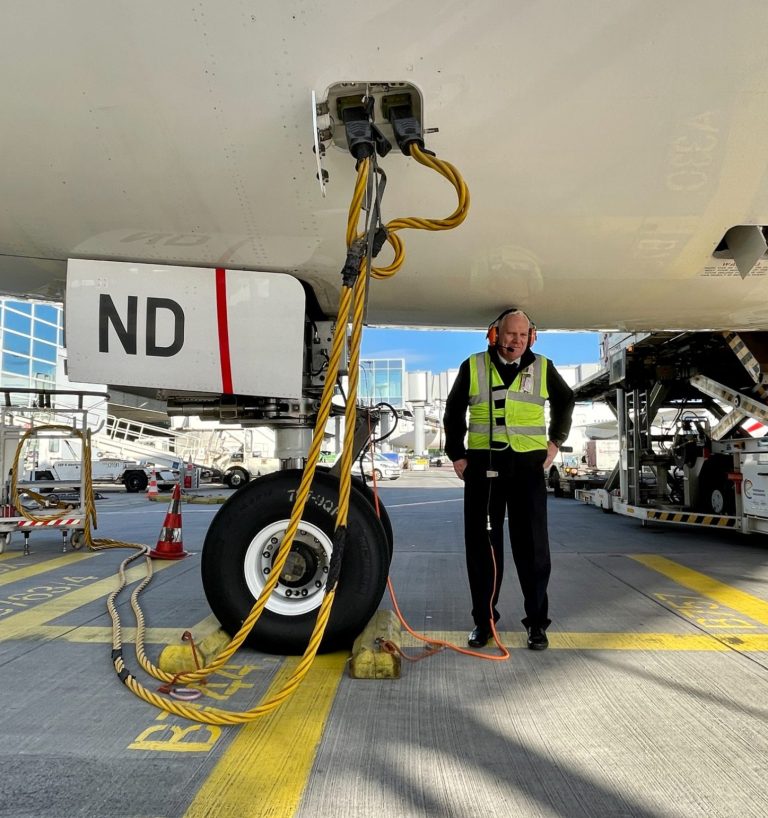 Flugzeug mit Fluggastbrücke und Gepäckwagen.